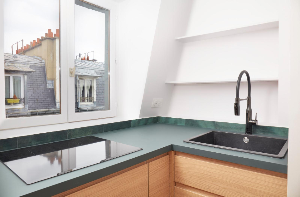 Cuisine contemporaine bois clair et plan de travail vert minéral.